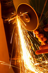 Man at work grinding iron pipe