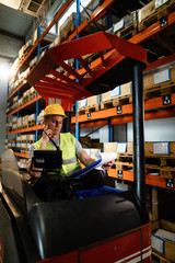 Fototapeta na wymiar Forklift driver checking his daily schedule in a distribution warehouse.