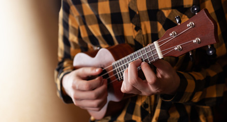 A young man playing ukulele in close up view