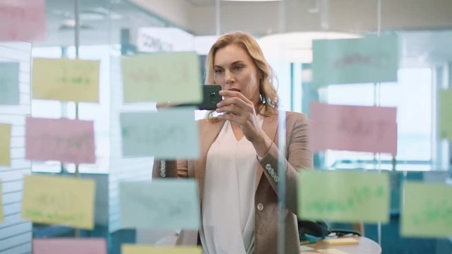 beautiful business woman using smartphone taking photo of sticky notes proud of successful problem solving strategy ideas with creative mind map working in office 4k