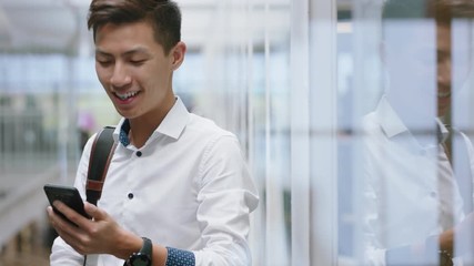 young asian businessman using smartphone texting messages on mobile phone sending email communication networking online at work in office - Powered by Adobe