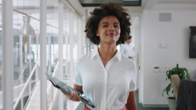 mixed race business woman smiling walking through office holding tablet computer enjoying successful career in corporate workplace 4k  