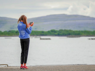 Girl teenager taking picture of a landscape on her smart phone. Concept: technology, photography, hobby