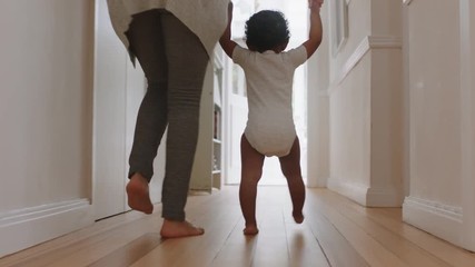 baby learning to walk toddler taking first steps with mother helping infant teaching child at home 