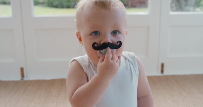 funny baby wearing moustache pacifier happy toddler sucking on dummy having fun cute infant enjoying silly humor at home 4k