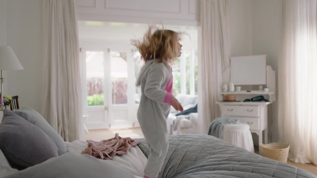 happy little girl dancing on bed having fun child in playful mood enjoying weekend morning at home