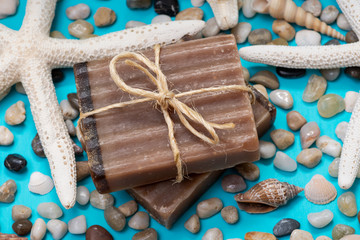 Handmade moisturizing Frankincense & Myrrh Goat's Milk Bar Soap decorated with small Pebbles, Sea Stars and Sea Shells on bright blue background.