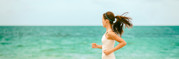 Fit woman training on outdoor cardio workout running on beach blue ocean background panoramic...