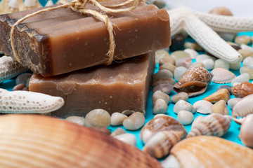 Handmade moisturizing Frankincense & Myrrh Goat's Milk Bar Soap decorated with small Pebbles, Sea Stars and Sea Shells on bright blue background.