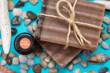 Handmade Frankincense & Myrrh Goat's Milk Bar Soap and Frankincense oil decorated with Pebbles, Sea Stars and Sea Shells on blue background.