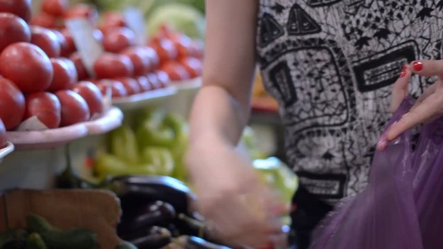 Close-up of a girl selects a cucumber at the supermarket.