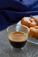 Cup of espresso on the background of the donuts on the plate and kitchen towel. Vertical.