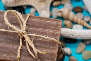 Handmade moisturizing Frankincense & Myrrh Goat's Milk Bar Soap decorated with small Pebbles, Sea Stars and Sea Shells on bright blue background.