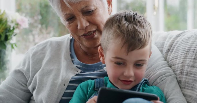 happy little boy using smartphone showing grandmother how to use mobile phone teaching granny modern technology intelligent child helping grandma at home 4k