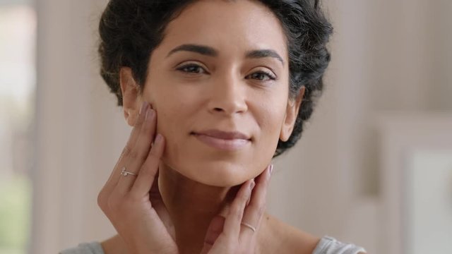 portrait beautiful young woman looking in mirror at perfect healthy skin touching face with hands enjoying smooth natural complexion with anti aging skincare getting ready at home beauty concept