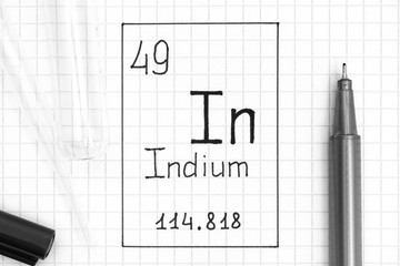 The Periodic table of elements. Handwriting chemical element Indium In with black pen, test tube and pipette.
