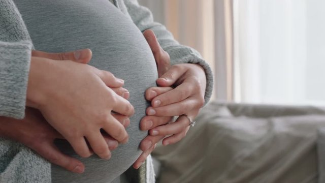 close up hands on pregnant belly proud couple embracing parenthood husband gently holding wife enjoying security excited for motherhood