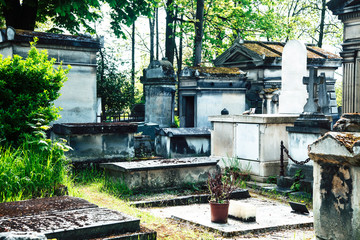 Tombstones in cemetery at dusk, gothic style crosses Paris