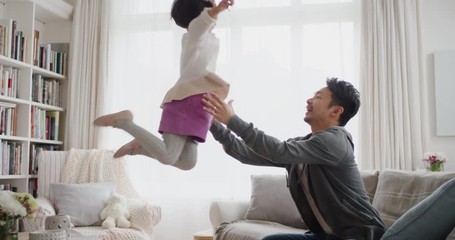 cute little asian girl jumping into fathers arms happy dad gently catching his daughter enjoying playful game with child at home 4k