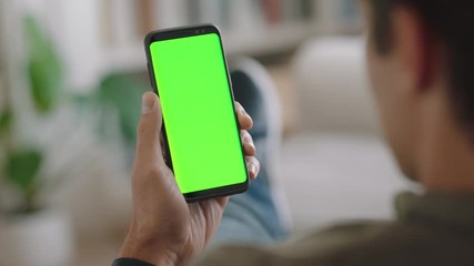 young man using smartphone watching green screen enjoying entertainment on mobile phone chroma key display horizontal orientation 4k footage - Powered by Adobe