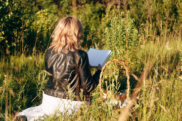 girl in field reading a book. The girl sitting on a grass, reading a book.