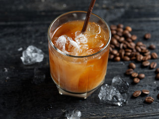 Cold coffee in a glass on a dark wooden table