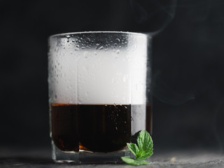 Alcoholic cocktail in a glass on a smoky black background