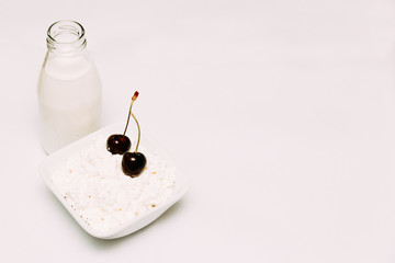 Milk in a bottle cottage cheese and cherry berries on a white background