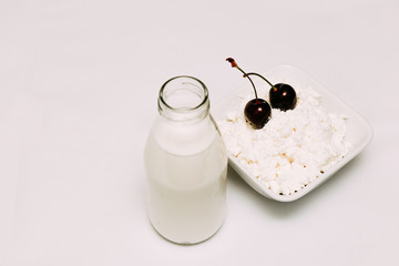 Milk in a bottle cottage cheese and cherry berries on a white background
