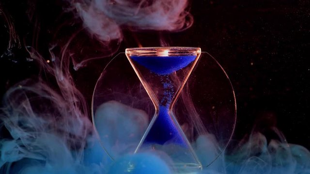 Falling sand silhouette in an hourglass with colorful bubble blur background