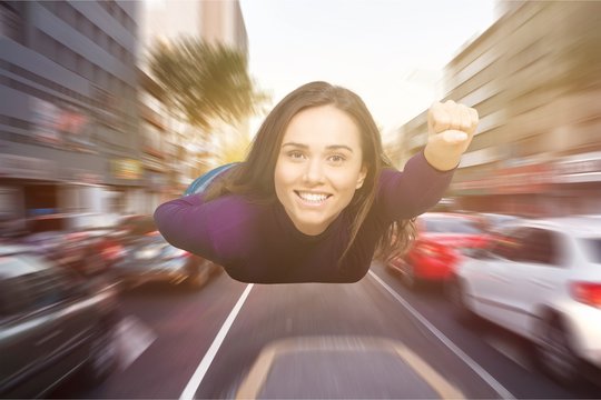 Young woman flying like superman on blurred street background