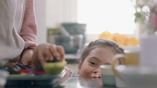 beautiful little girl stealing cupcake with mother baking in kitchen sneaky child enjoying delicious treats having fun at home