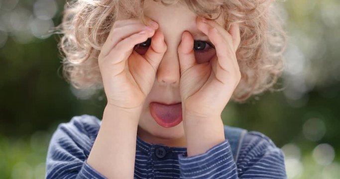 portrait funny little boy making faces having fun kid enjoying making silly expressions in sunny park 4k