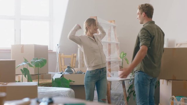 young couple moving into new home owners high five enjoying successful property investment hugging in house exciting real estate move 4k footage
