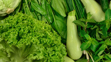 Fresh green vegetables and herbs as a background.