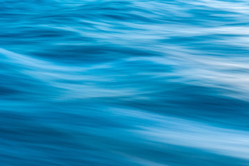 Fototapeta na wymiar Gentle soothing silky flowing natural ocean water movement. Abstract background motion blur. Serene and peaceful deep blue sea in nature.