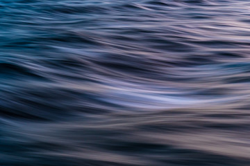 Fototapeta na wymiar Gentle soothing silky flowing natural ocean water movement. Abstract background motion blur. Serene and peaceful deep blue sea in nature.