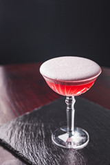 Clover Club Cocktail with Gin, Lemon Juice, Raspberries, and Egg White Foam in a Glass in a Dark Luxurious Bar