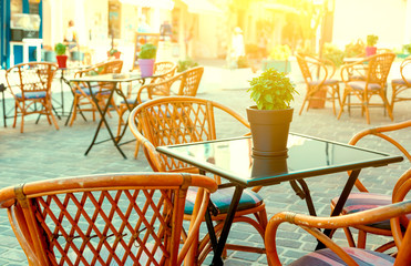 Pot with a flower in center of table on background of the Sunny city of Chania. tourists, Crete Greece. depth of field, blur Chania.Street Cafe.