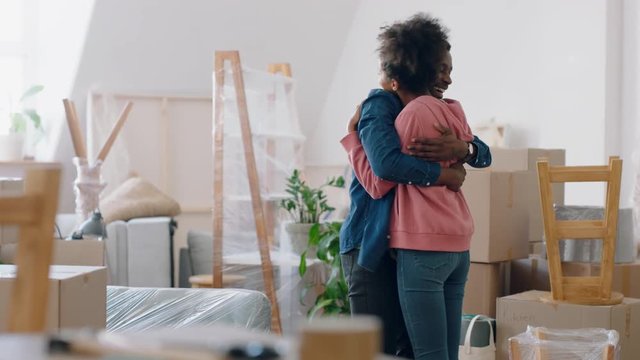 young mixed race couple moving into new home dancing enjoying successful property investment hugging in house exciting real estate move 4k footage
