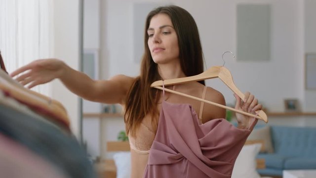 beautiful young woman getting dressed looking in mirror choosing outfit fashion choice putting on clothes enjoying positive self image feeling confident at home 4k footage