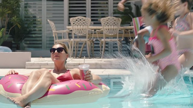 funny children jumping in swimming pool splashing mother relaxing on swim tube kids playfully surprise mom family having fun on sunny day enjoying summer 4k
