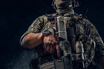 Closeup photo shoot of man's hand holding machine gun. Man is wearing military uniform and wach.