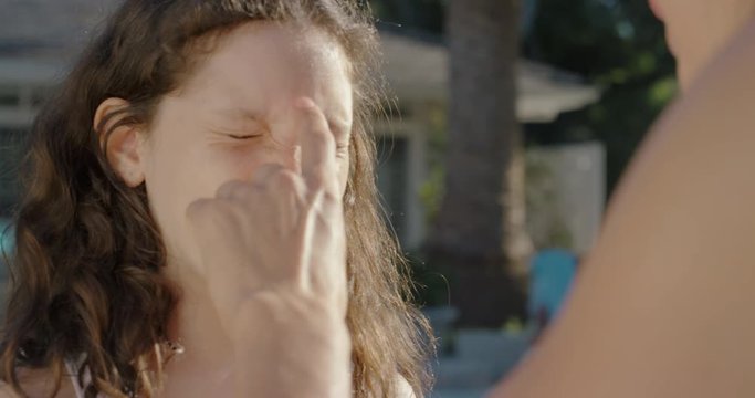mother applying sunblock lotion on daughters skin for sun protection little girl getting ready to swim in pool with mom using sunscreen caring for childs health on sunny day 4k