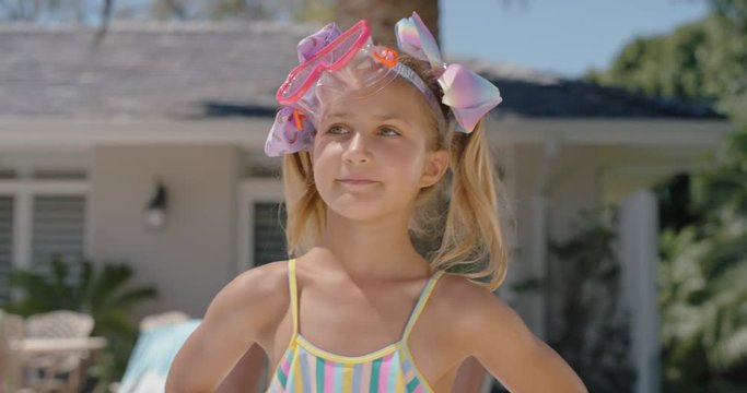 funny little girl smiling walking outdoors enjoying warm summer day by swimming pool cute kid wearing goggles at home on vacation 
