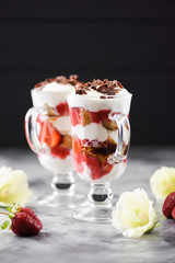 Healthy berry dessert. Strawberry tiramisu in glasses on dark background