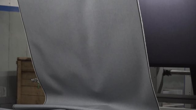 Brilliant smooth tilting shot of freshly woven denim being produced from a machine.