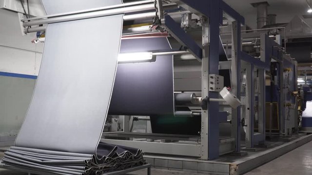 Stunning wide angle shot of a large, automated machine producing denim in a denim manufacturing facility.