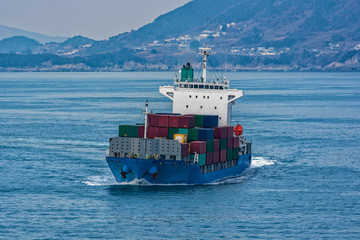 Overloaded cargo container vessel approaching port of transhipment on delivery.