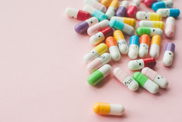 Colored capsule on a pastel pink background